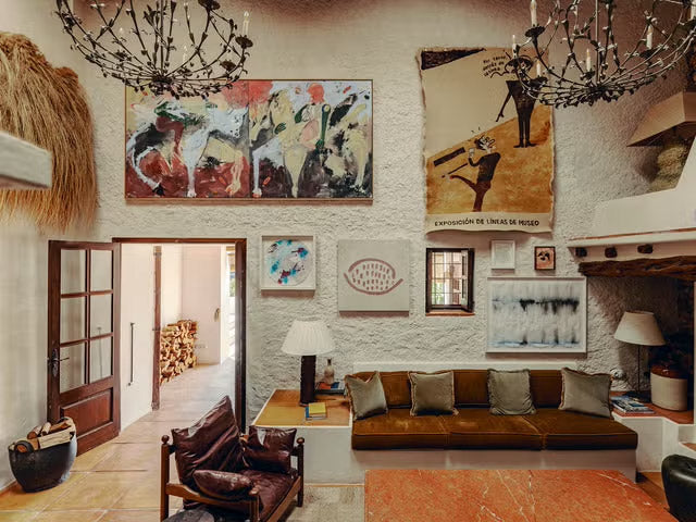 Living room with a brown sofa, wooden coffee table, and various wall art.