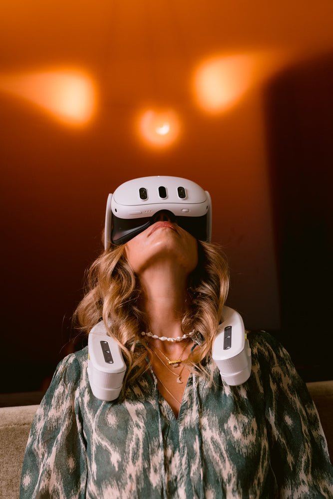 woman wearing a white VR headset and white shoulder straps against an orange wall.